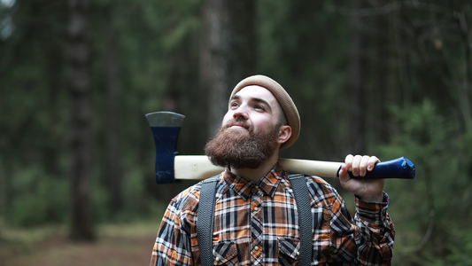 A lumberjack bearded man with plaid shirt and an axe.